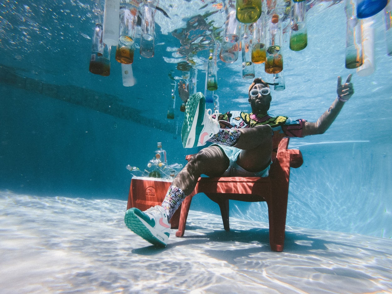 man sitting on a chair underwater with floating bottles