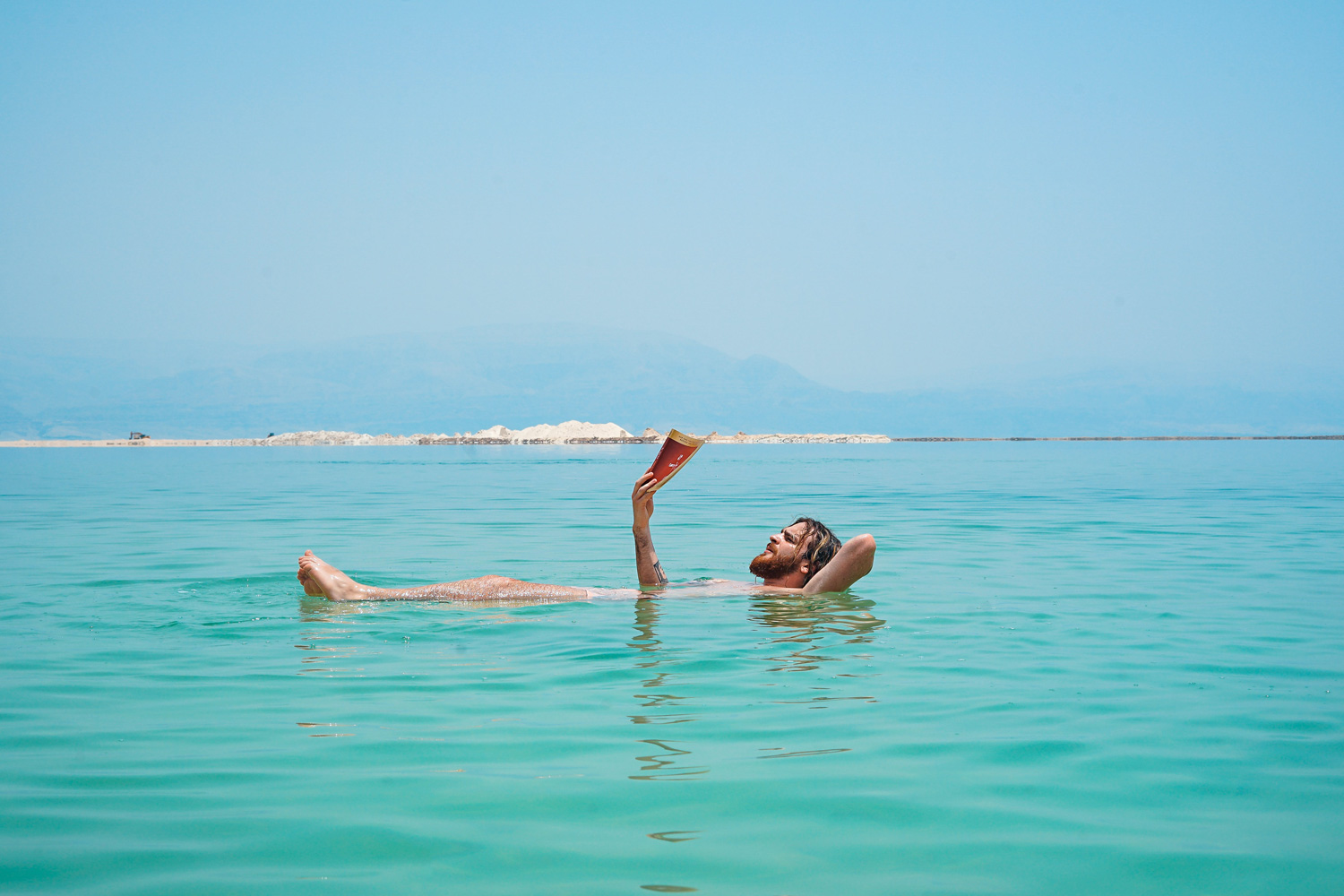 man floating and reading in the dead sea
