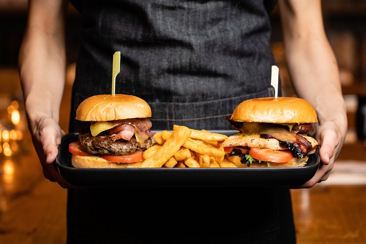 man holding a tray with hamburgers