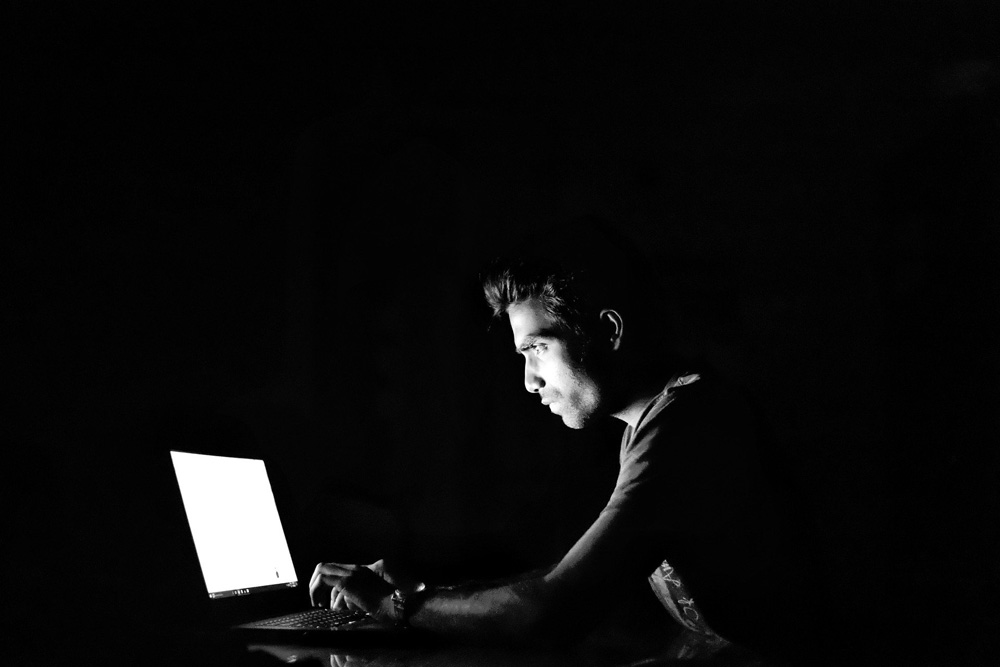 man using laptop in darkness