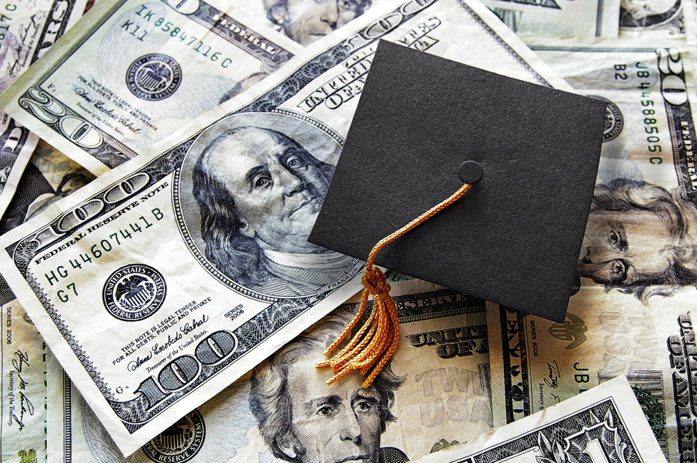 graduation cap on top of a pile of money debt