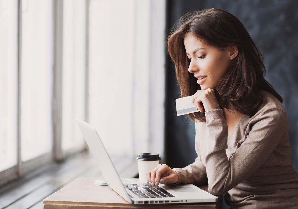 woman sitting with laptop holding credit card