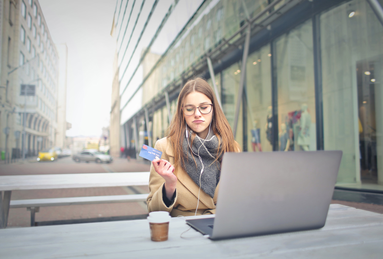 woman sitting outside with a laptop holding a credit card